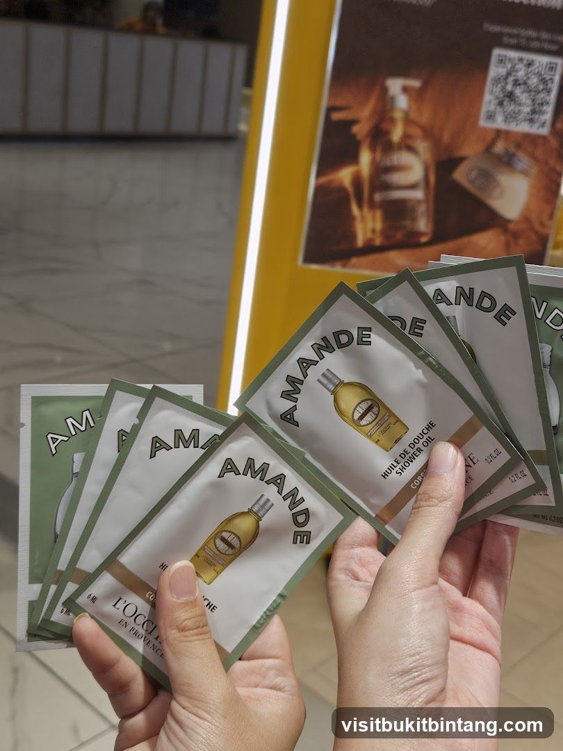 Hand holding sample packets of L'Occitane Almond Shower Oil