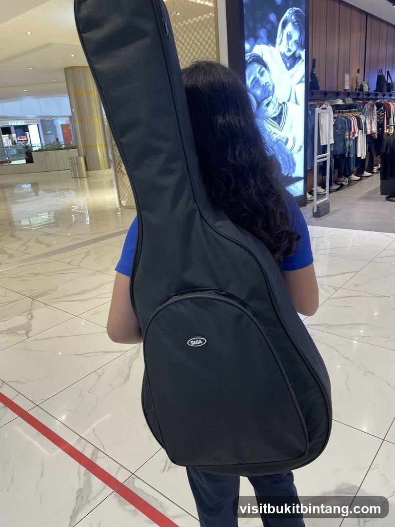 Person carrying a guitar case in a mall