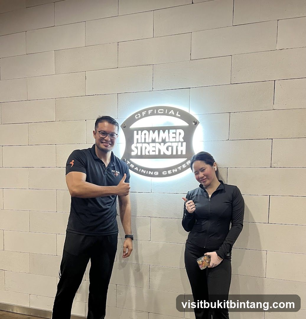 Two people posing in front of a Hammer Strength sign