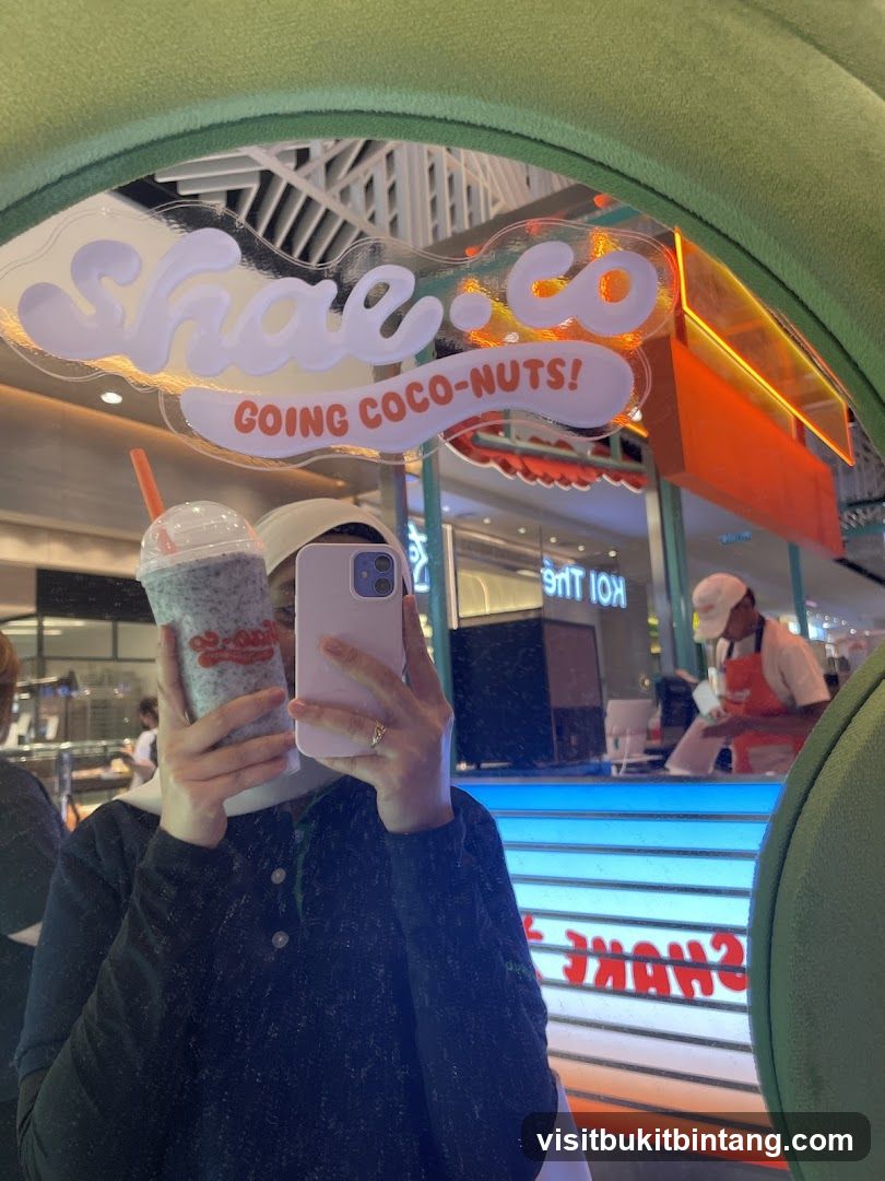 Person holding a drink in front of a mirror reflecting a shop