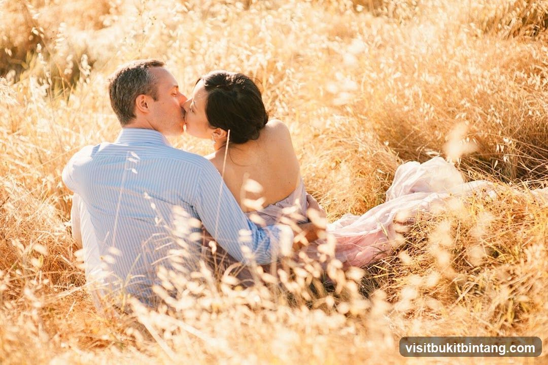 Couple kissing in a field of dry grass