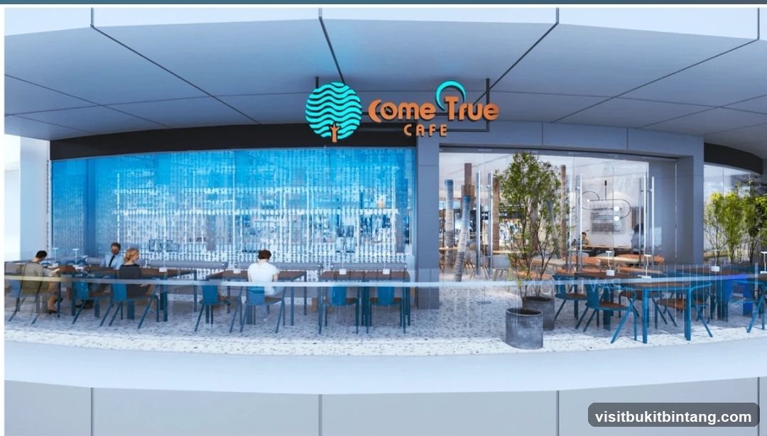 The exterior of a cafe with a modern design. The cafe has large glass windows and doors, allowing a view of the interior seating area. A prominent sign above the entrance reads "Come True Cafe" with a stylized logo. Inside, tables and chairs are set up, and there are plants adding to the ambiance. The facade features a blue, patterned glass wall on one side.