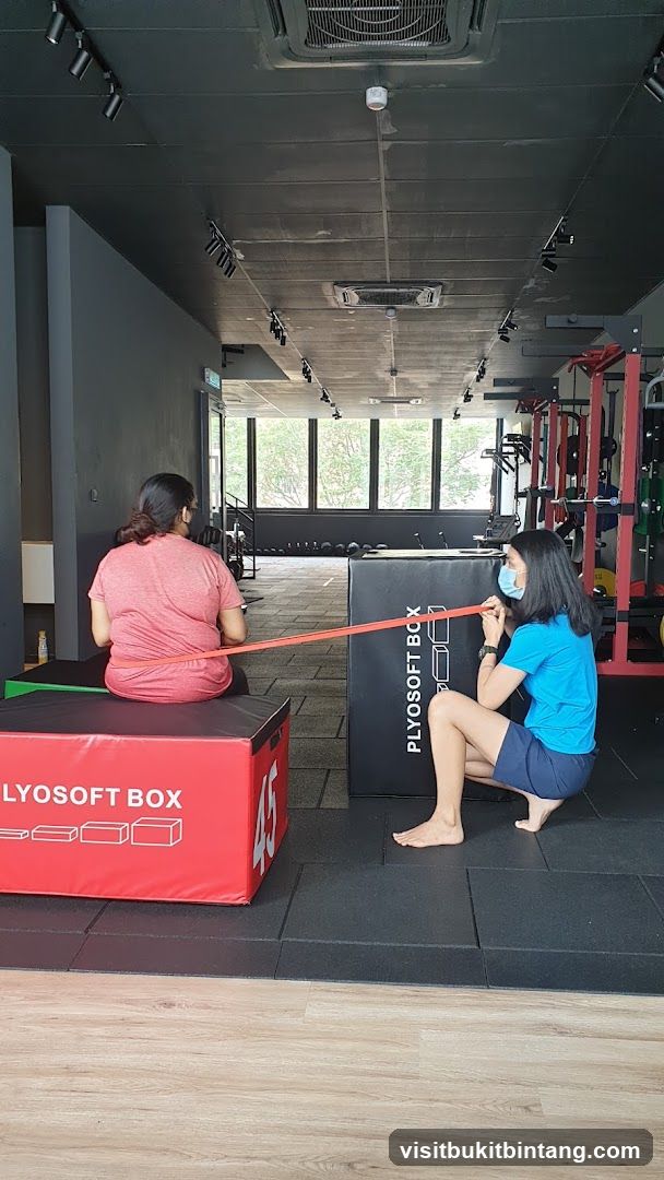 Two people exercising with a resistance band in a gym