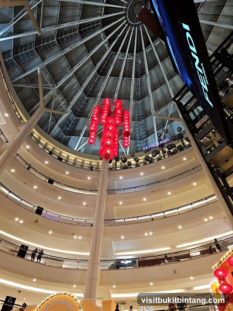 Interior of a multi-level shopping mall with a large dome ceiling and red lantern decorations.