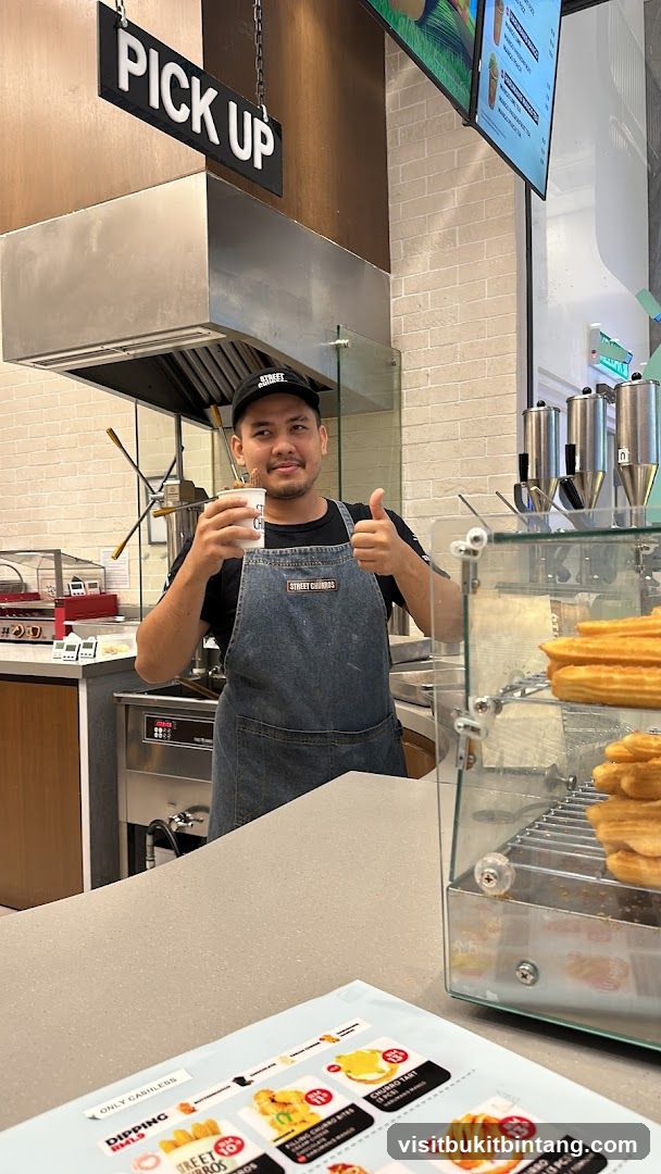 Staff member holding a drink and giving a thumbs up