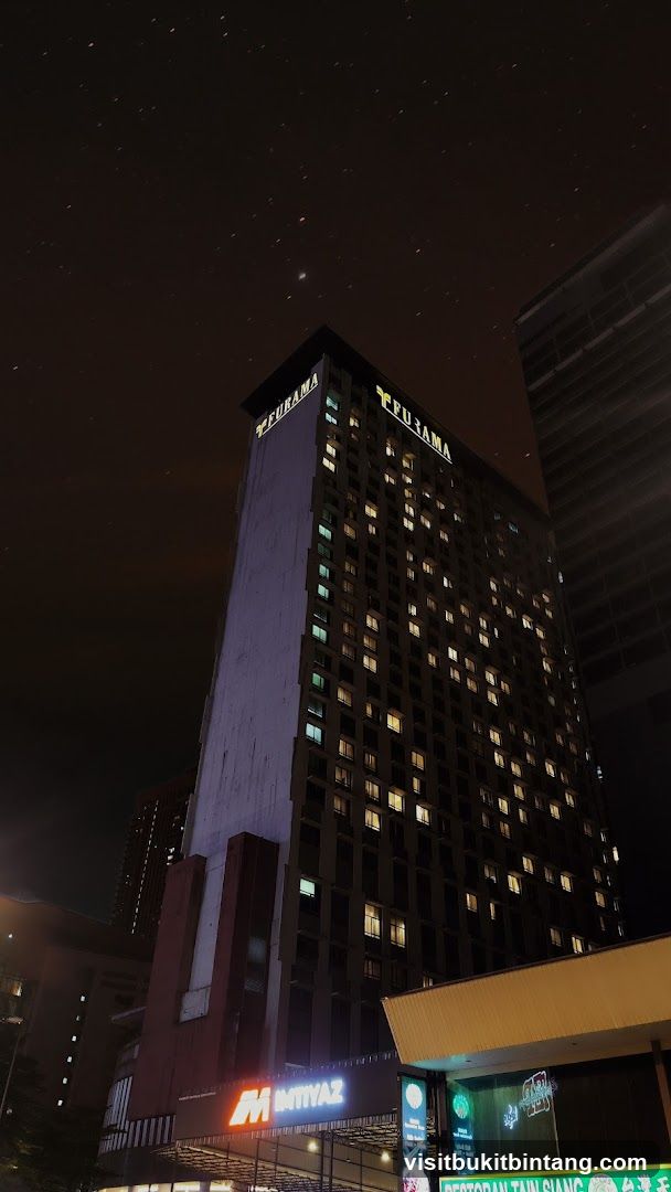 Nighttime view of a tall building with illuminated windows and signage