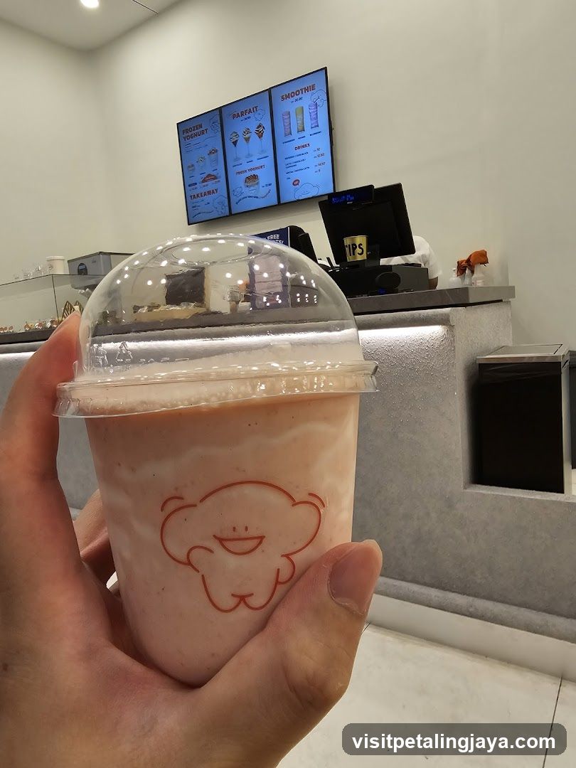 Hand holding a pink smoothie in a store