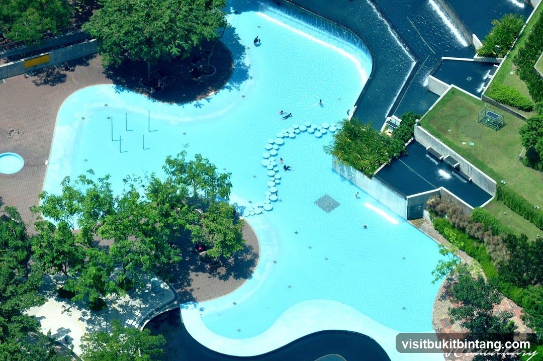 Aerial view of a public swimming pool with surrounding greenery and architecture.