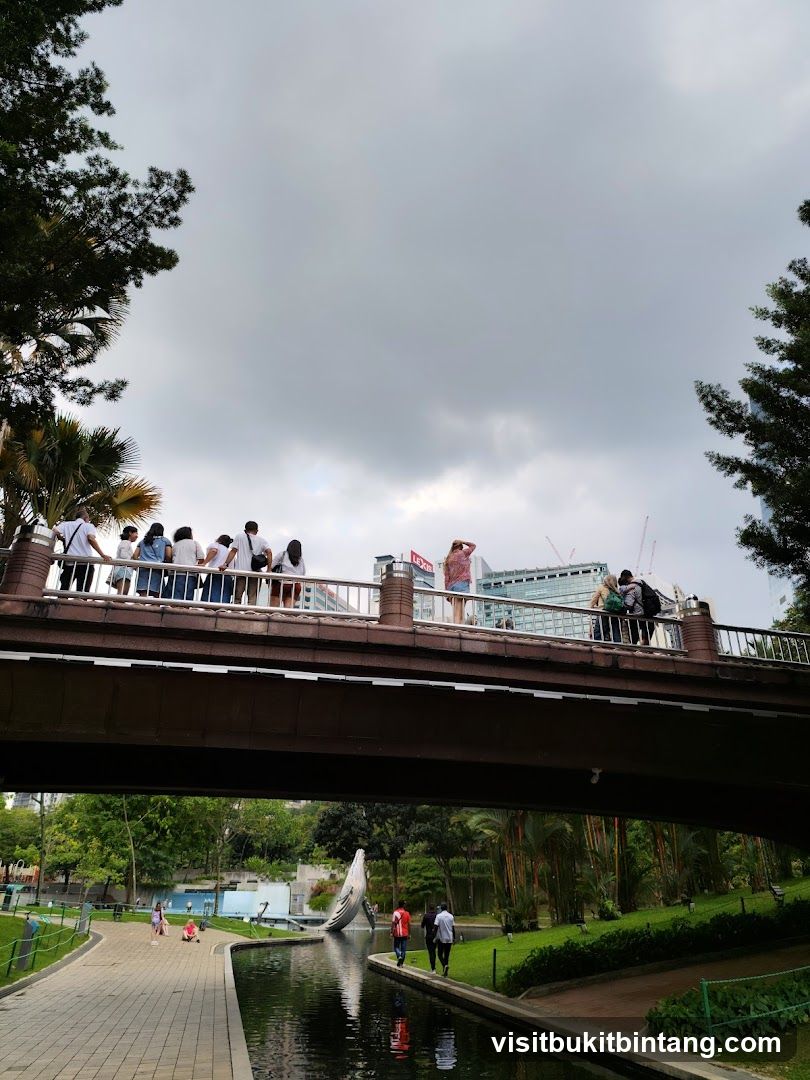 People on a bridge over a park with a canal
