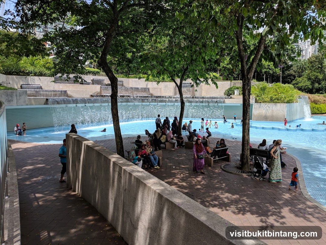People enjoying a public pool with waterfalls