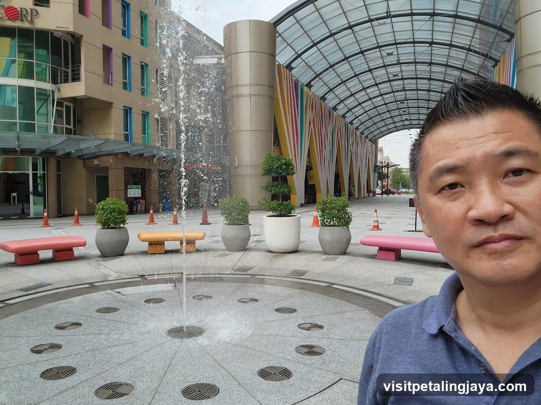 Outdoor plaza with fountain and person selfie