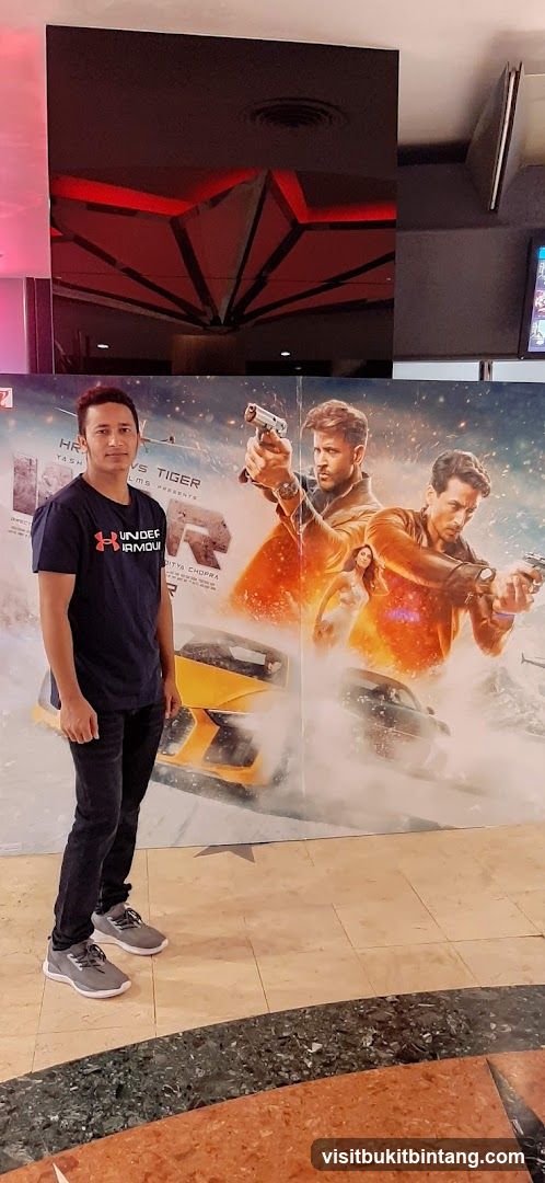 Man Poses in Front of Movie Poster