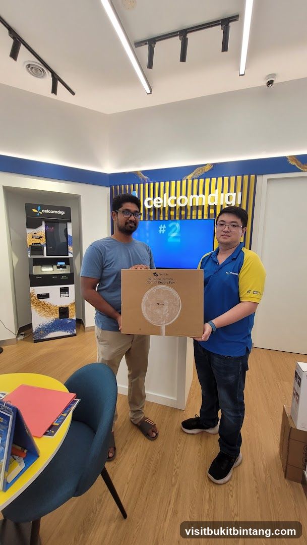 Two men holding a box with a fan inside
