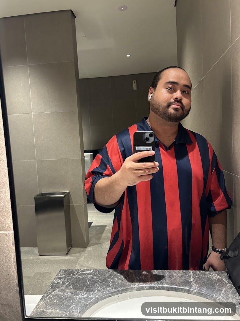 Man in striped shirt taking a mirror selfie