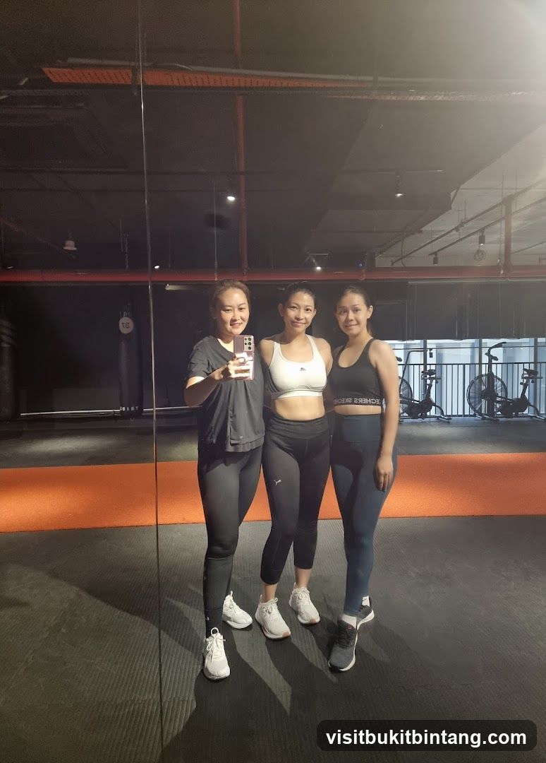 Three women in athletic wear posing for a mirror selfie in a gym.