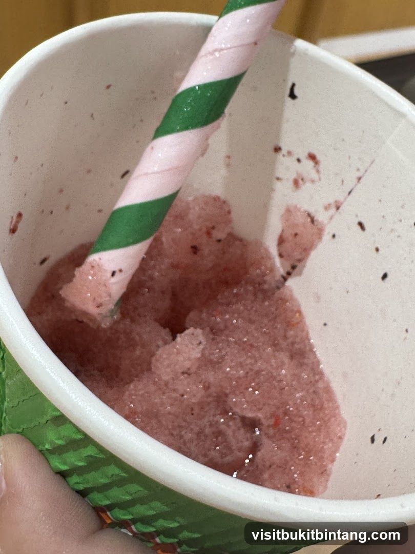 Close-up of a pink slushy with a striped straw
