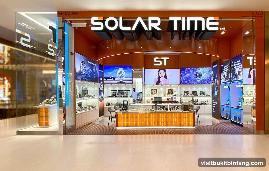 A well-lit watch store with a prominent "SOLAR TIME" sign. The storefront features large display screens showcasing watches and models, with glass display cases filled with timepieces. The interior is modern and organized, with orange accents on the counter and shelving.