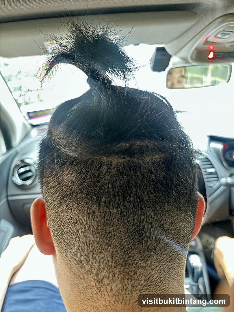 Man with a top knot in a car