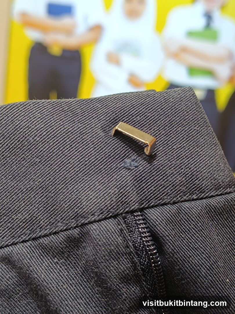 Close-up of dark fabric with a metal clasp and zipper