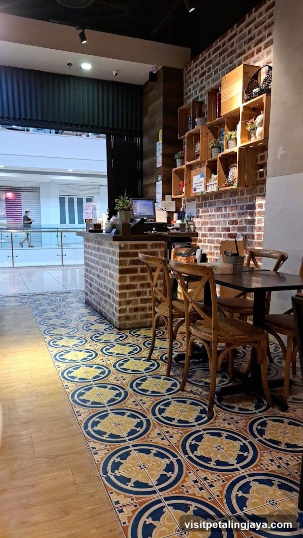 Interior of a cafe with brick walls and patterned floor tiles.