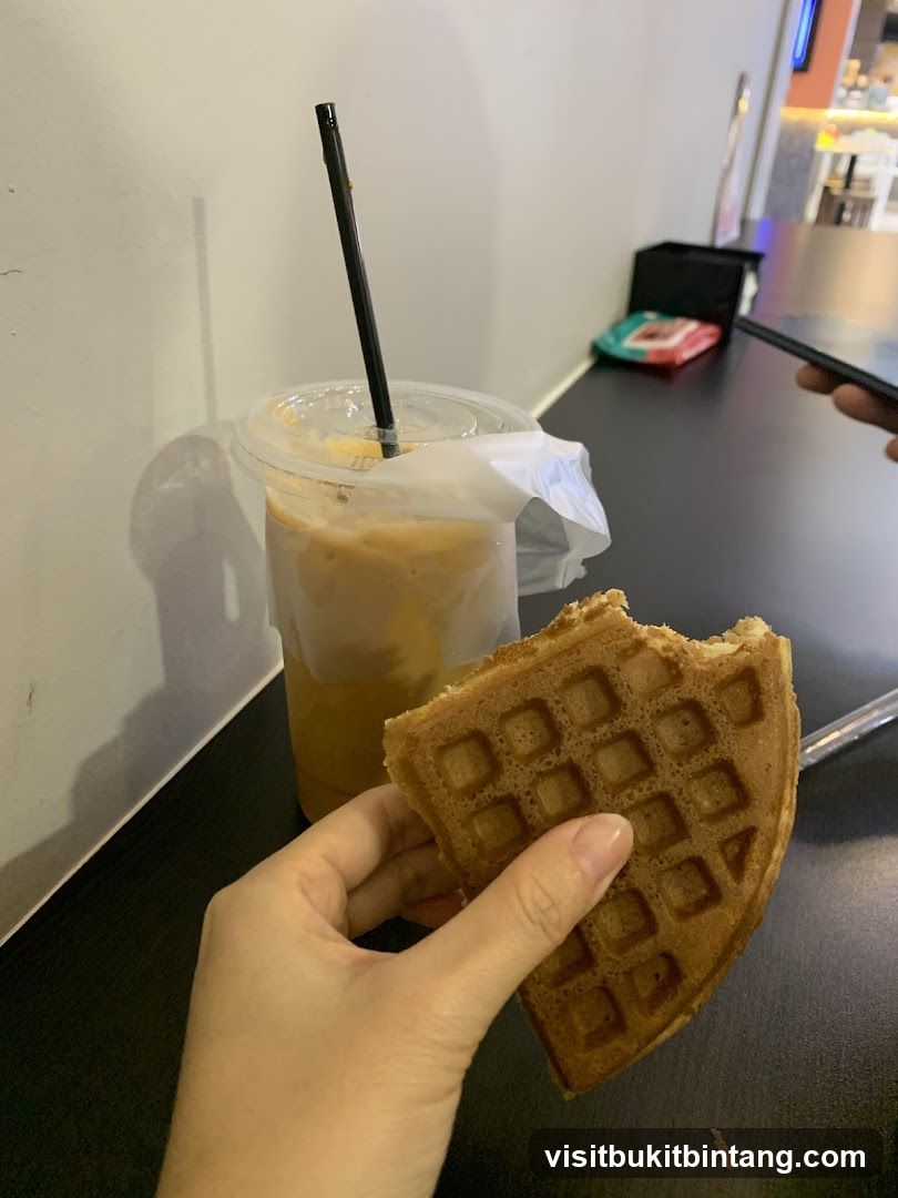 Hand holding a waffle with a coffee drink
