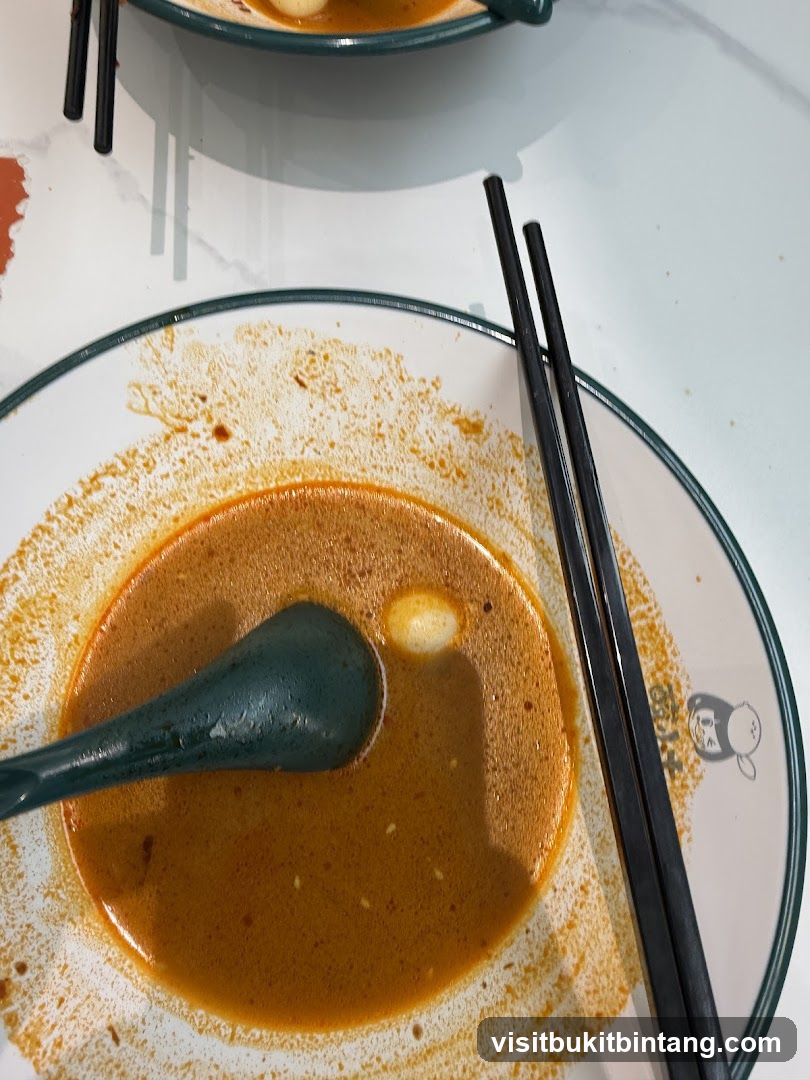 Close-up of a bowl of soup with chopsticks and a spoon