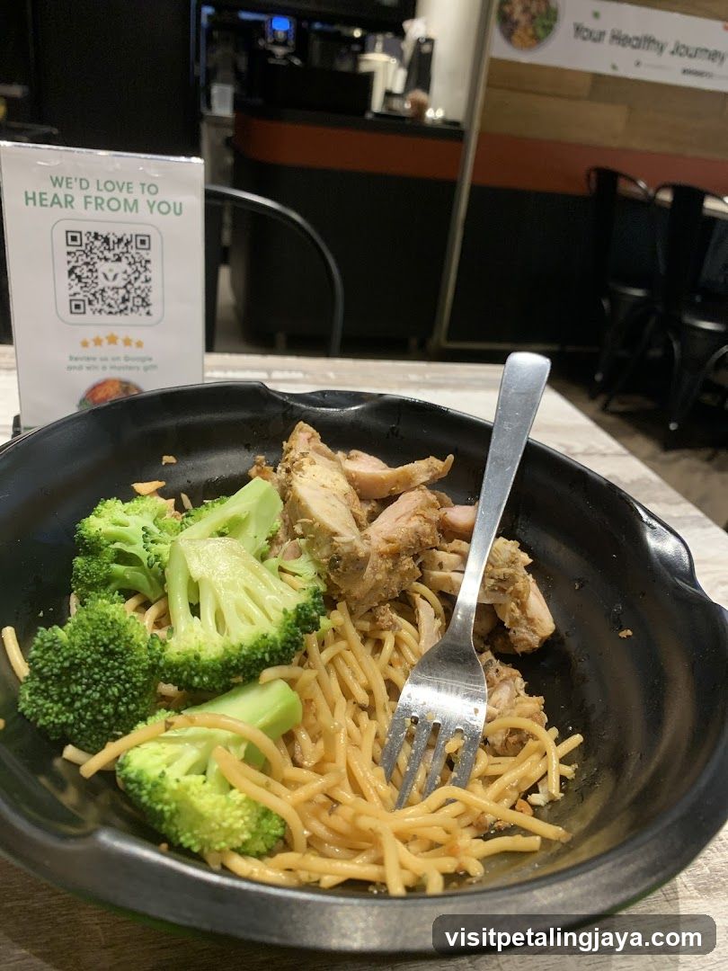 Noodle dish with broccoli and chicken in a black bowl