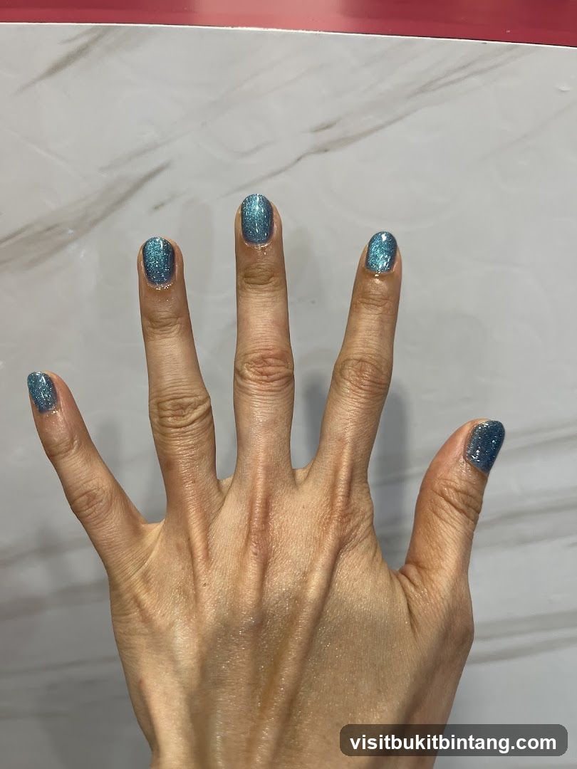 Hand with Blue Glitter Nail Polish