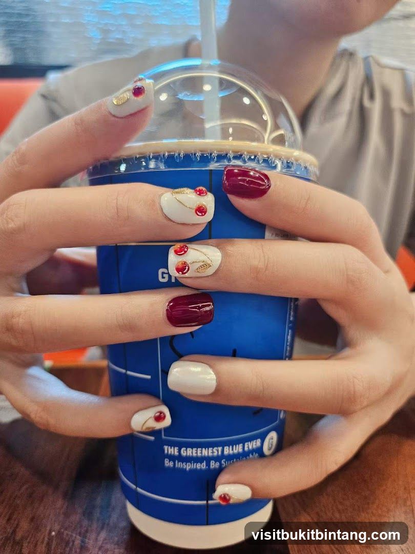 Hands holding a blue cup with cherry-themed nails