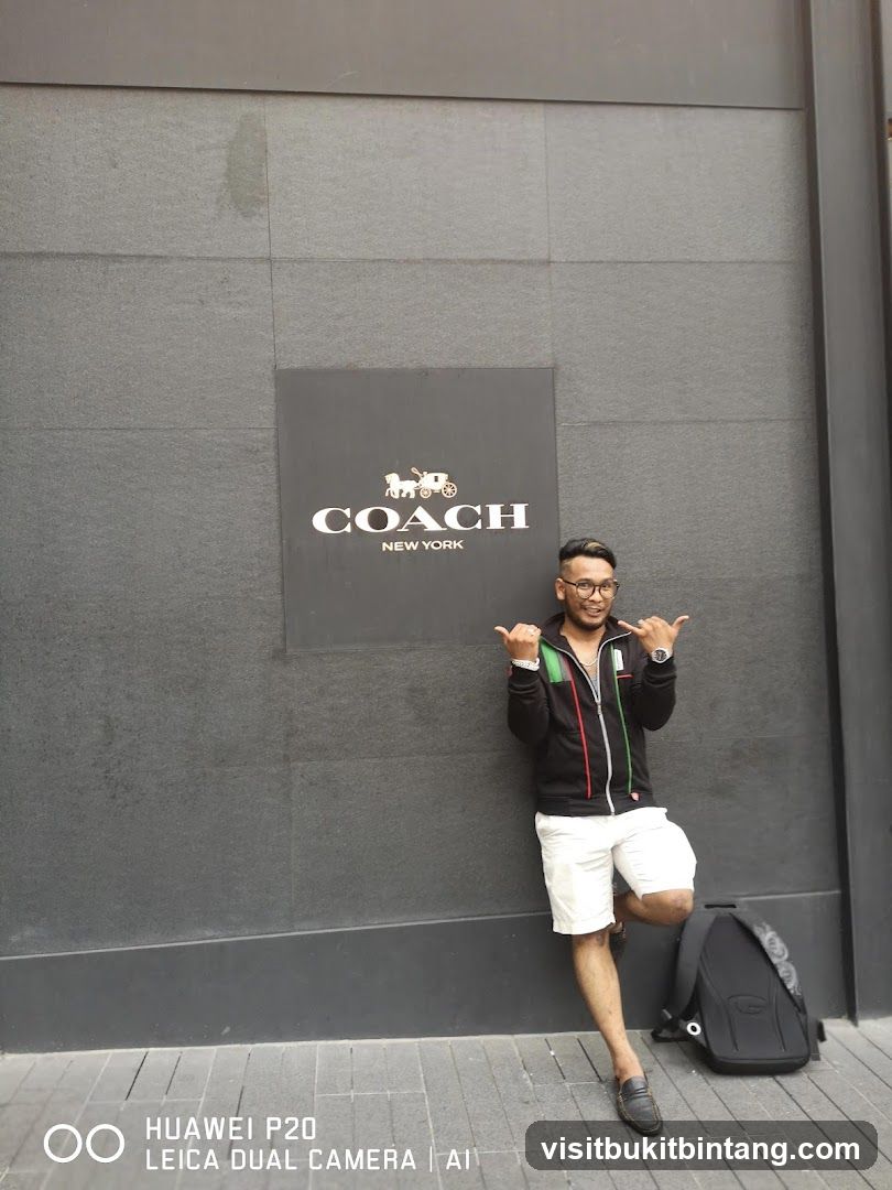 Man posing in front of Coach New York logo