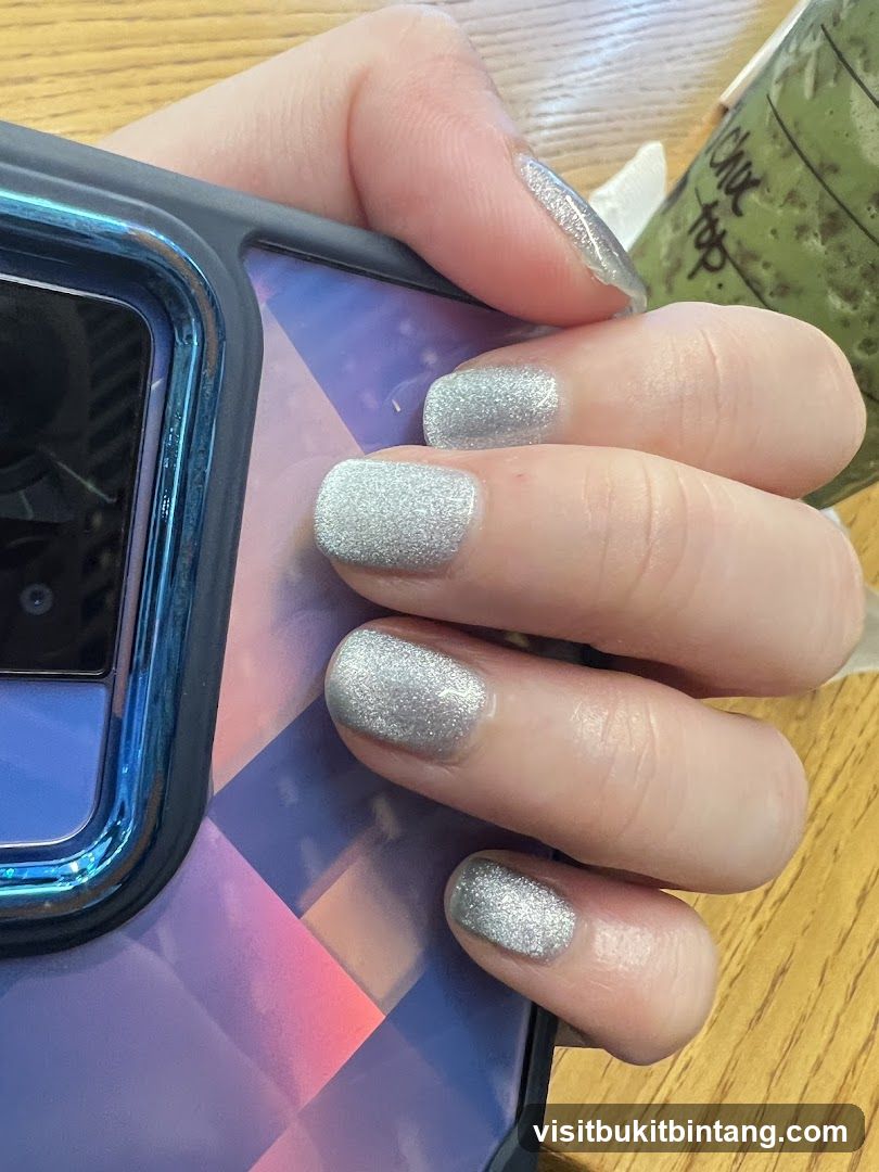 Hand with Glittery Nails Holding a Phone