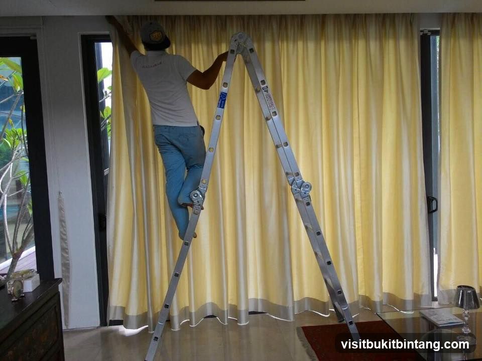 Man on Ladder Adjusting Curtains