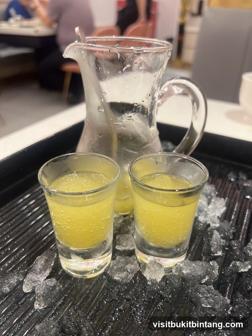 Two shots of yellow liquid with a pitcher